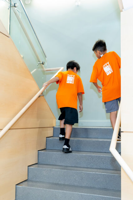 2 citysquash players walk up the stairs to the courts level